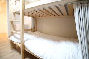 Una cama individual con estructura de madera y ropa de cama blanca.