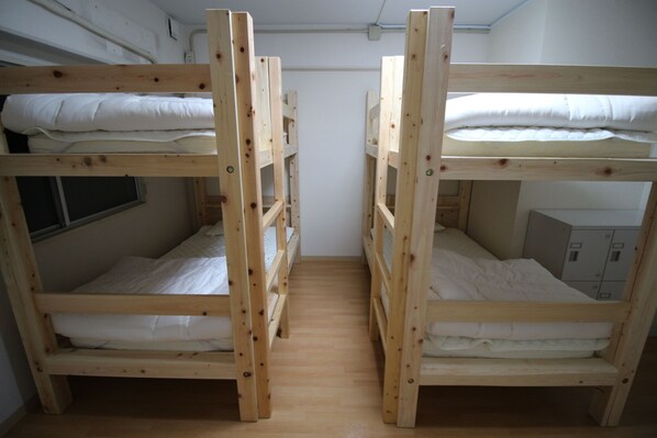 Una habitación con dos literas de madera, una ventana y un armario pequeño.