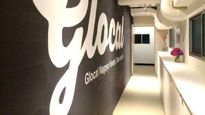 A hallway with a large wall sign reading "Glocal Nagoya Hostel, Cafe and Bar". - Glocal Nagoya Backpackers Hostel (Nagoya)