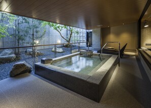 A modern indoor pool with clear glass walls, a stone deck, and a minimalist design. - Fukui Manten Hotel Ekimae (Fukui)