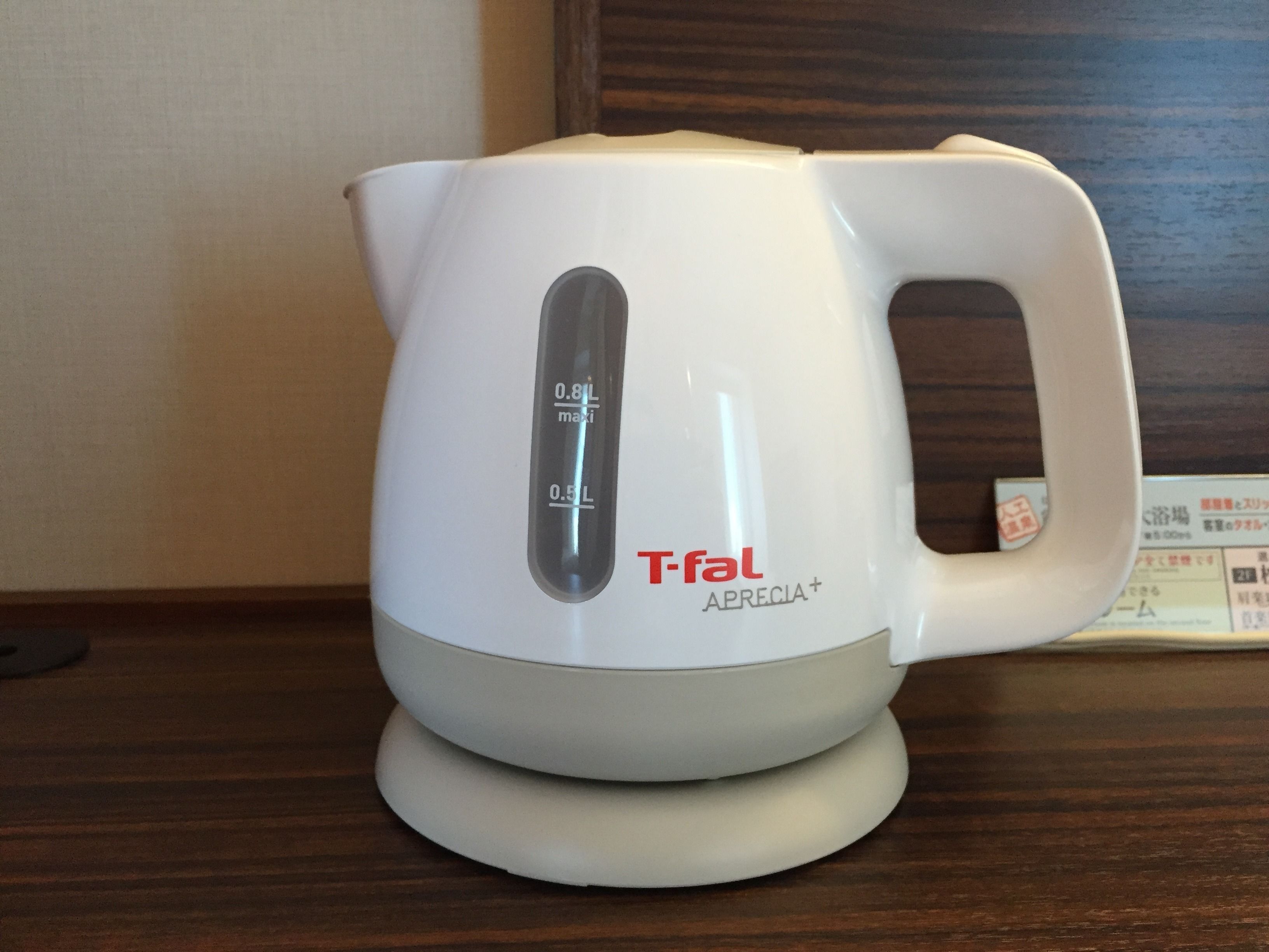 A white electric kettle with a digital display on a wooden surface.