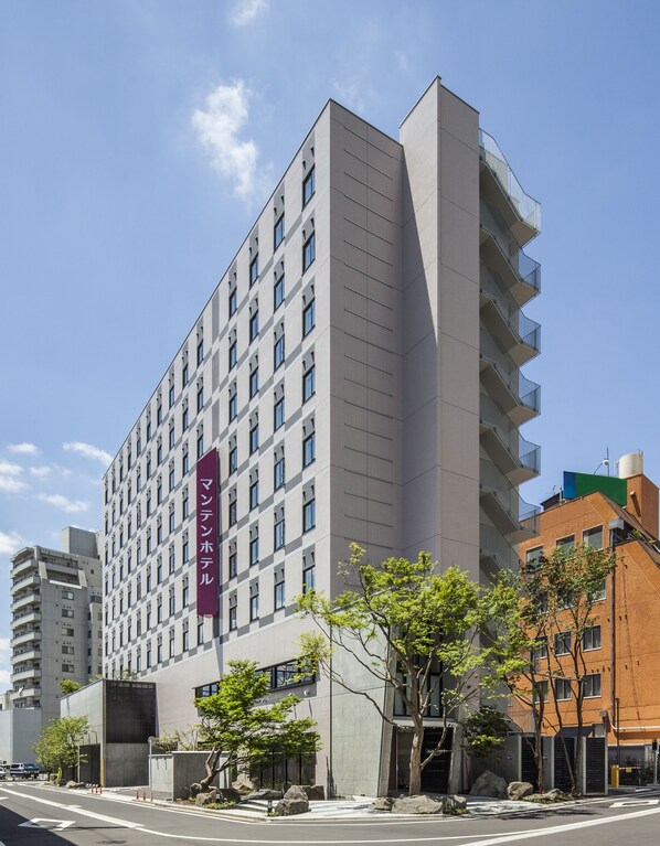 A modern multi-story hotel with a prominent red sign, large windows, and a flat roof. - Fukui Manten Hotel Ekimae (Fukui)