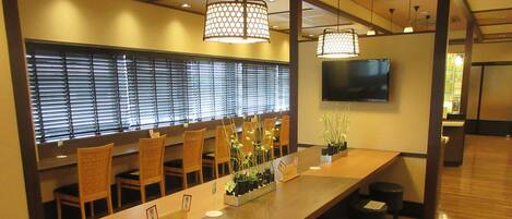 A conference room with a long table, chairs, a TV, and potted plants.