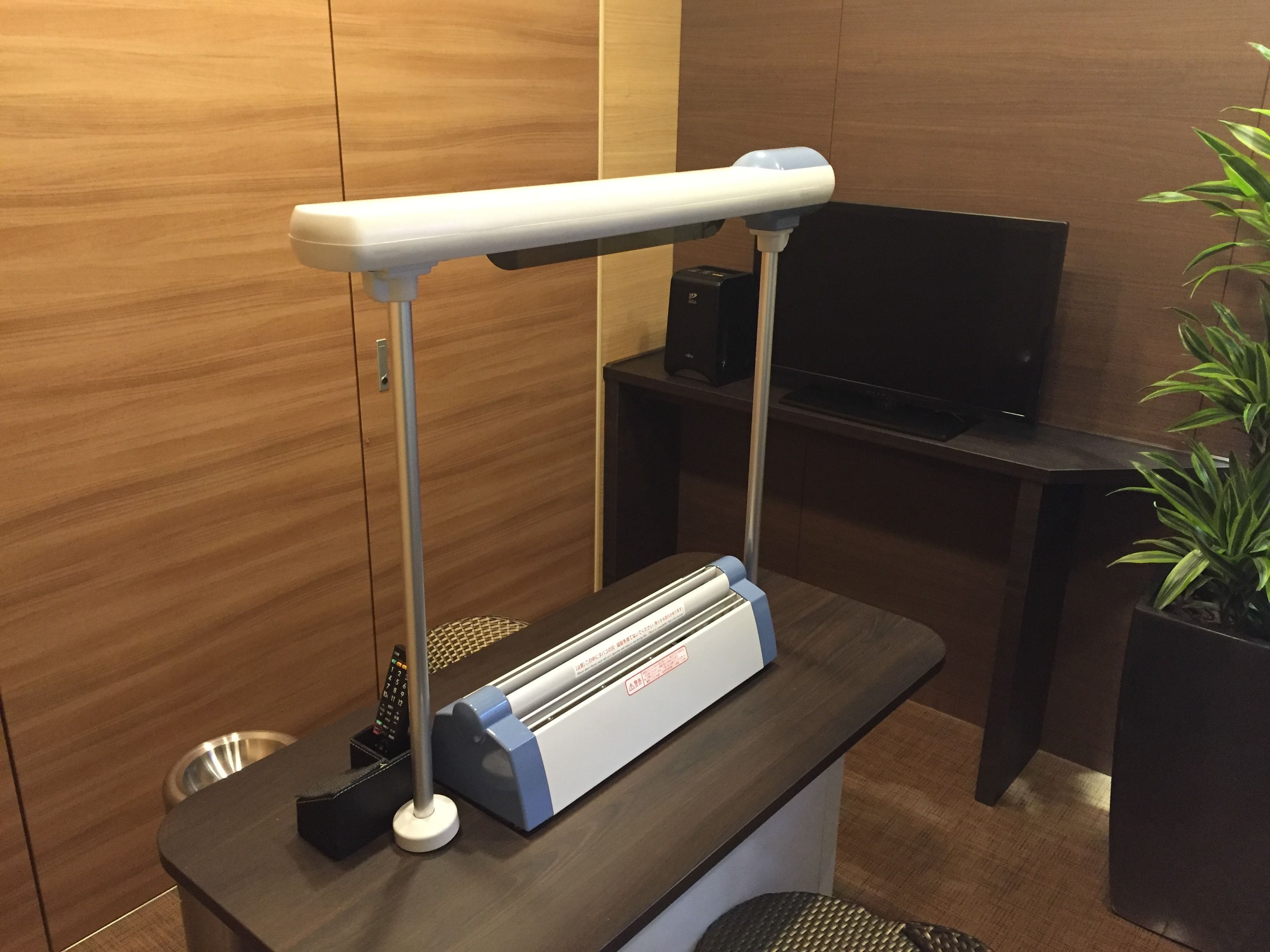 A desk with a desk lamp, a speaker, and a plant.
