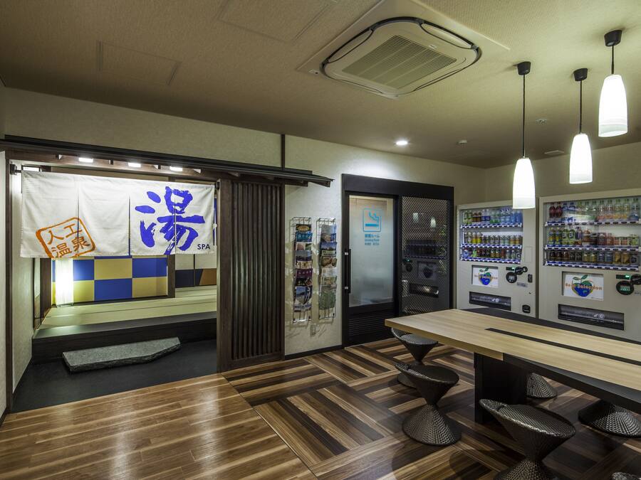 Interior moderno com piso de madeira, balcão de recepção, máquinas de venda automática e placa indicando spa.