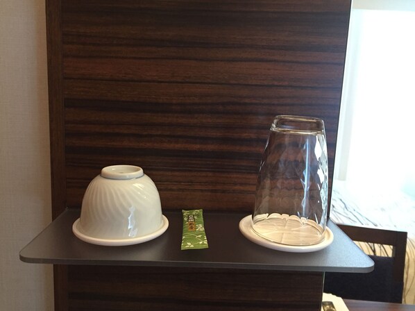 Una mesa con dos recipientes blancos de cerámica y un paquete verde sobre una mesa de madera oscura, con una pared de madera de fondo.