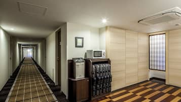 A hotel hallway with a checkered carpet, a vending machine, a microwave, and a sliding door closet.