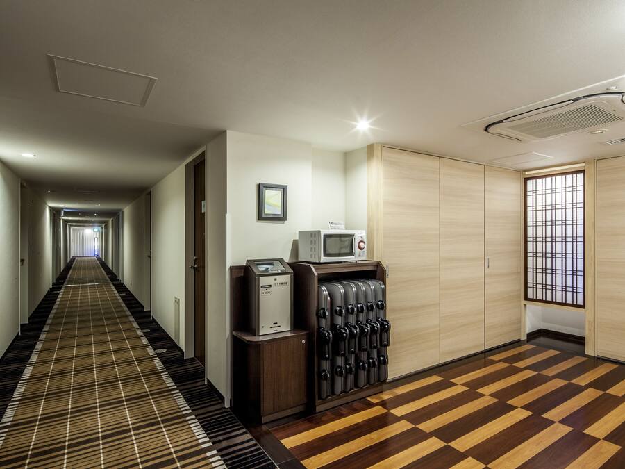 A hotel hallway with a checkered carpet, a vending machine, a microwave, and a sliding door closet.