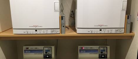 Two identical white washing machines on wooden shelves, each with a digital display and a control panel.