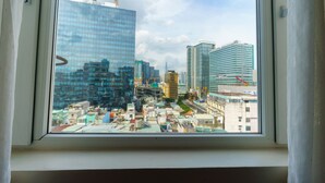 A cityscape through a window with modern buildings, including a prominent glass skyscraper. - Roseland Corp Hotel (Ho Chi Minh City)