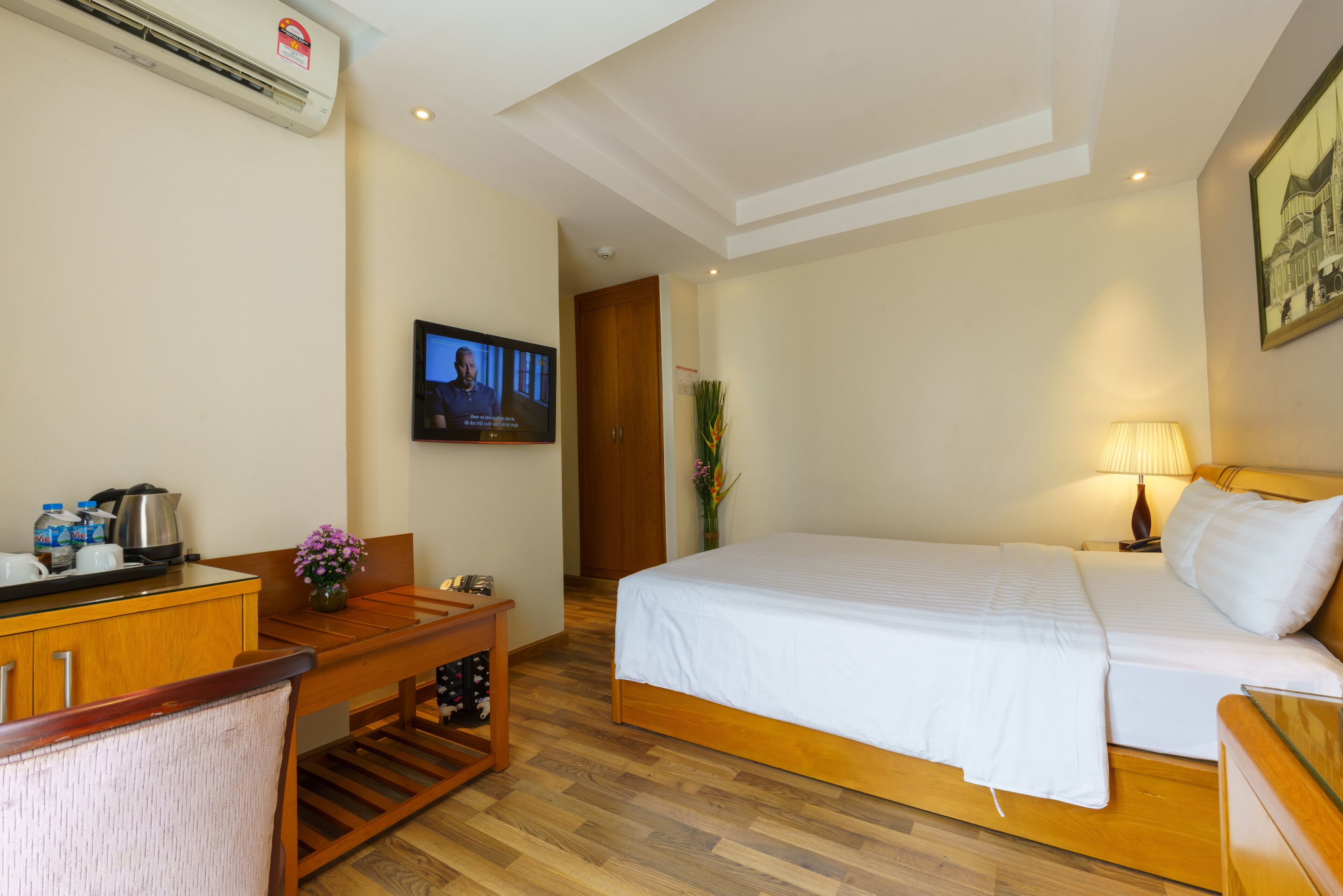Een hotelkamer met een bed, een bureau met stoel, een televisie en een lamp.