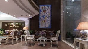 A lobby with a seating area featuring a sofa, armchairs, and a small table with a vase of flowers. - Roseland Corp Hotel (Ho Chi Minh City)