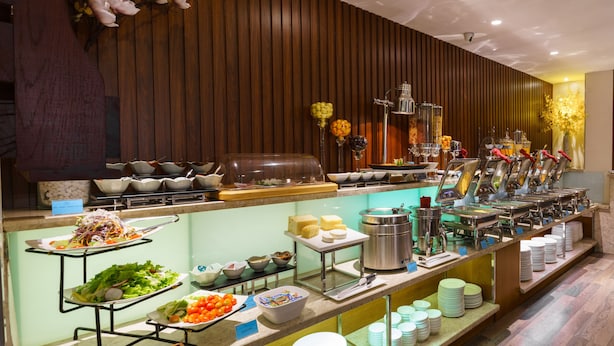 A buffet setup with various food items and utensils. - Roseland Corp Hotel (Ho Chi Minh City)