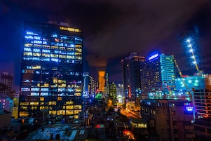 A nighttime cityscape with illuminated buildings, including a hotel with a visible sign.