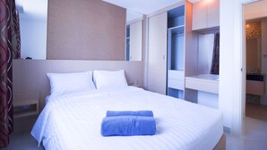 Une chambre d’hôtel moderne avec un lit bien fait, une armoire intégrée et une petite table de chevet.