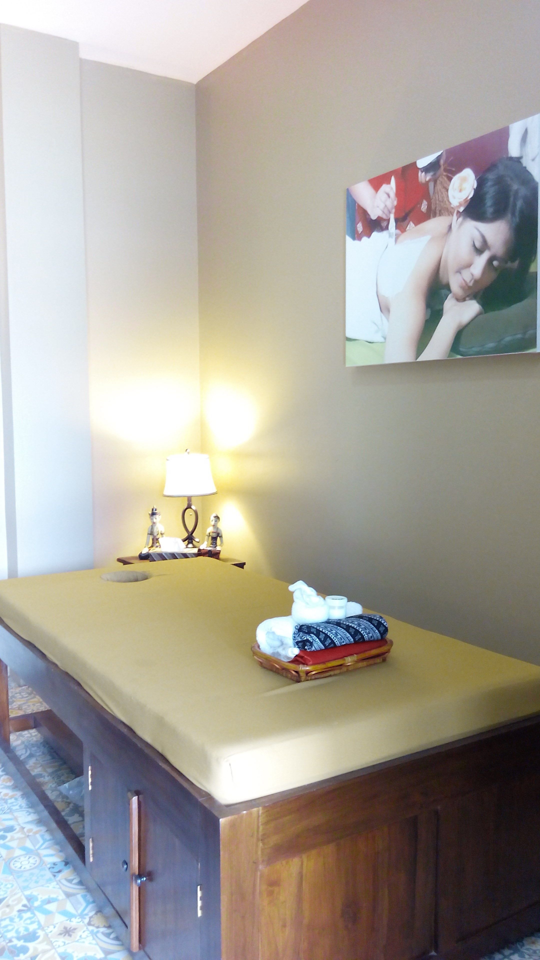 Una habitación con cama, una mesita de noche con lámpara y un cuadro enmarcado en la pared.