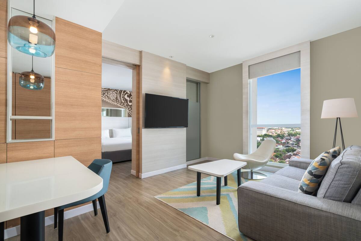 Una sala de estar moderna con una televisión de pantalla plana, un sofá, una mesa de comedor y vistas a la ciudad.