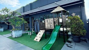 Un área de juegos infantiles con un tobogán, pared de escalar y una pequeña mesa con sillas.