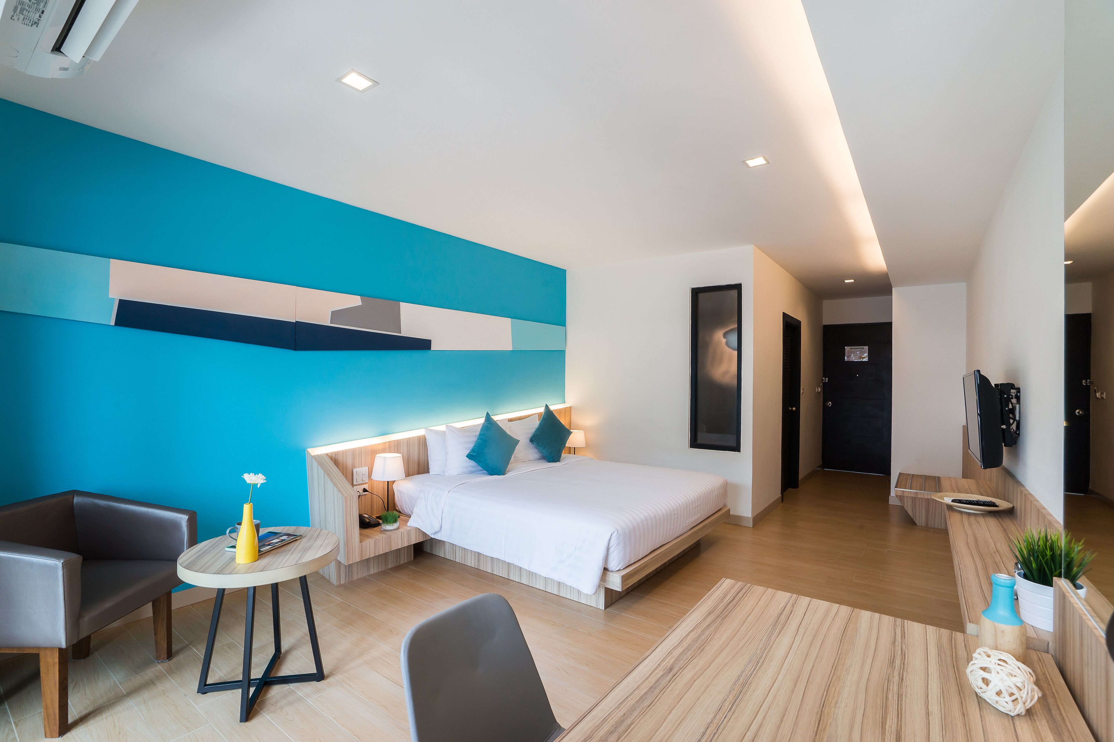 Une chambre d’hôtel moderne dotée d’un grand lit, de tables de chevet, d’un bureau et d’un coin salon.
