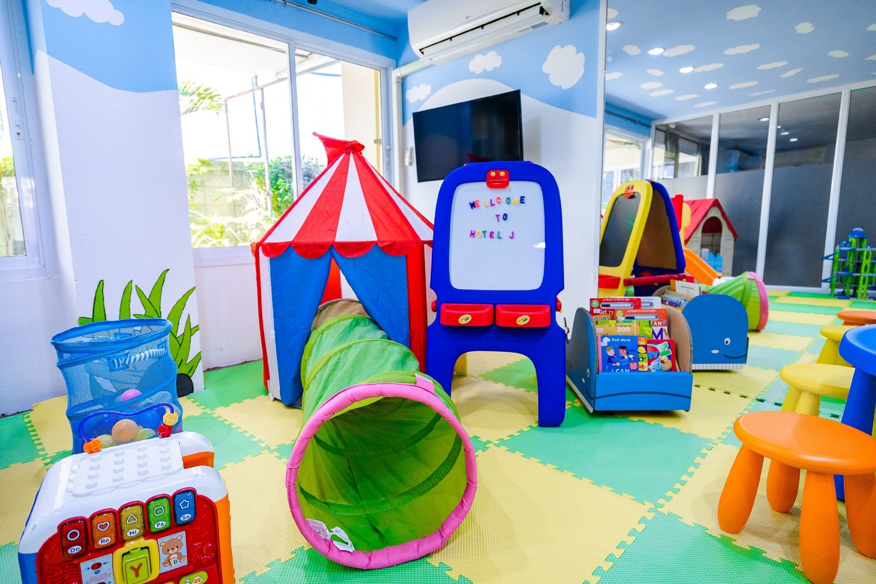 A children's play area with a playhouse, a tunnel, and a welcome sign.