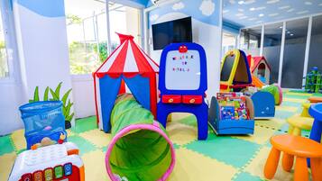 A children's play area with a playhouse, a tunnel, and a welcome sign.