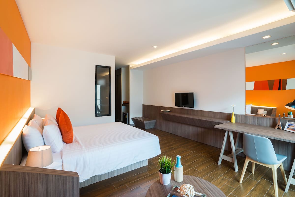 A modern hotel room with a bed, desk, and seating area.