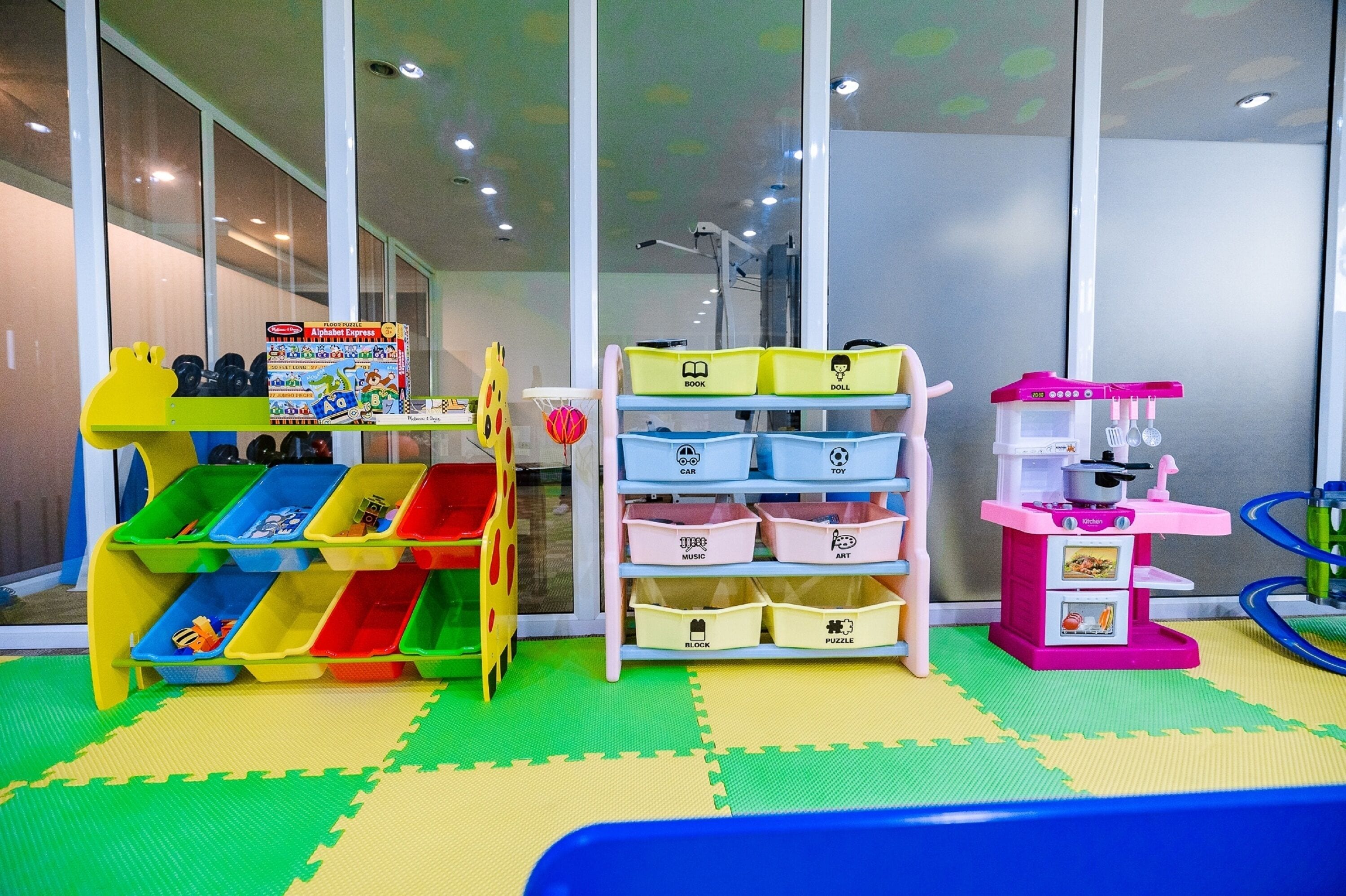 A children's play area with a slide, shelves with labeled bins, and a toy kitchen.