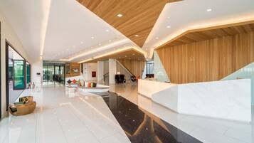 Un vestíbulo amplio con techo de madera, una mesa de recepción y una escalera.