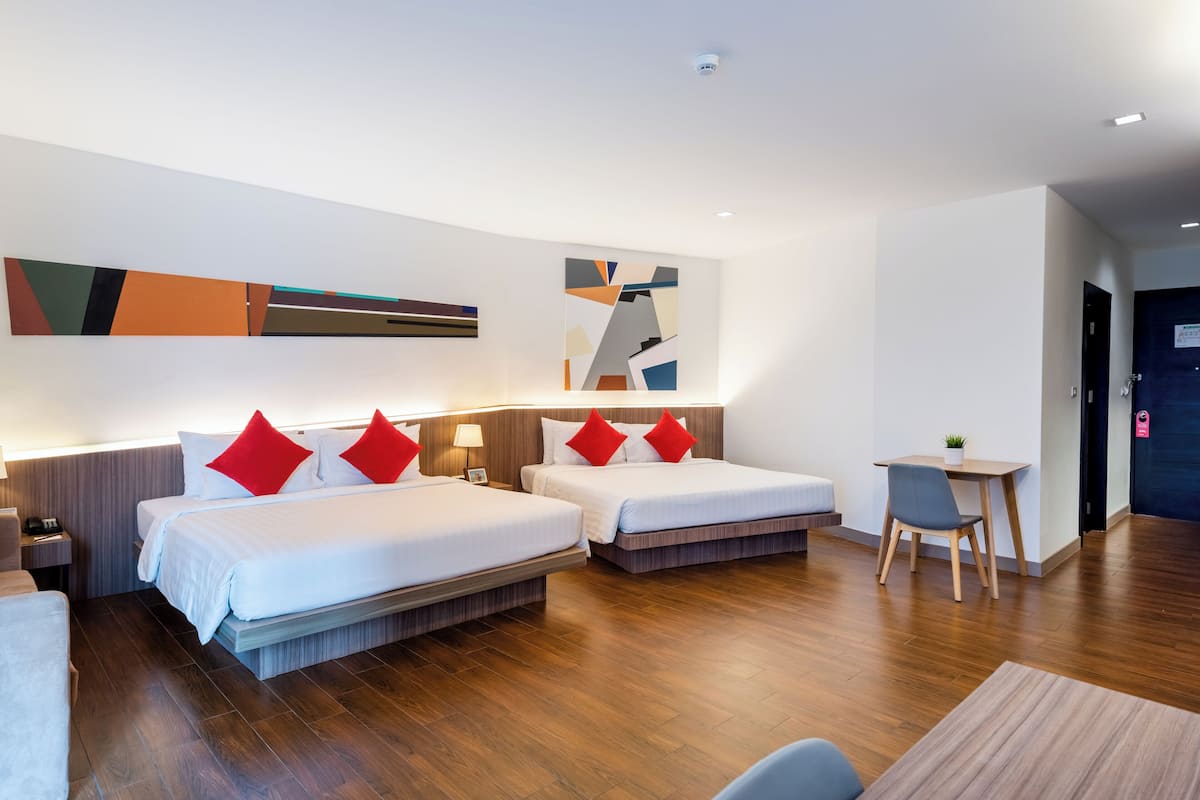 A hotel room with two beds, a desk, and a chair.