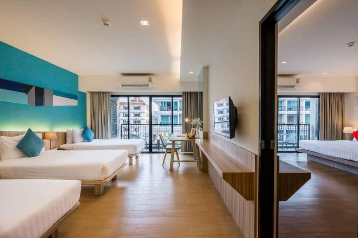 A hotel room with two beds, a desk, and a TV.