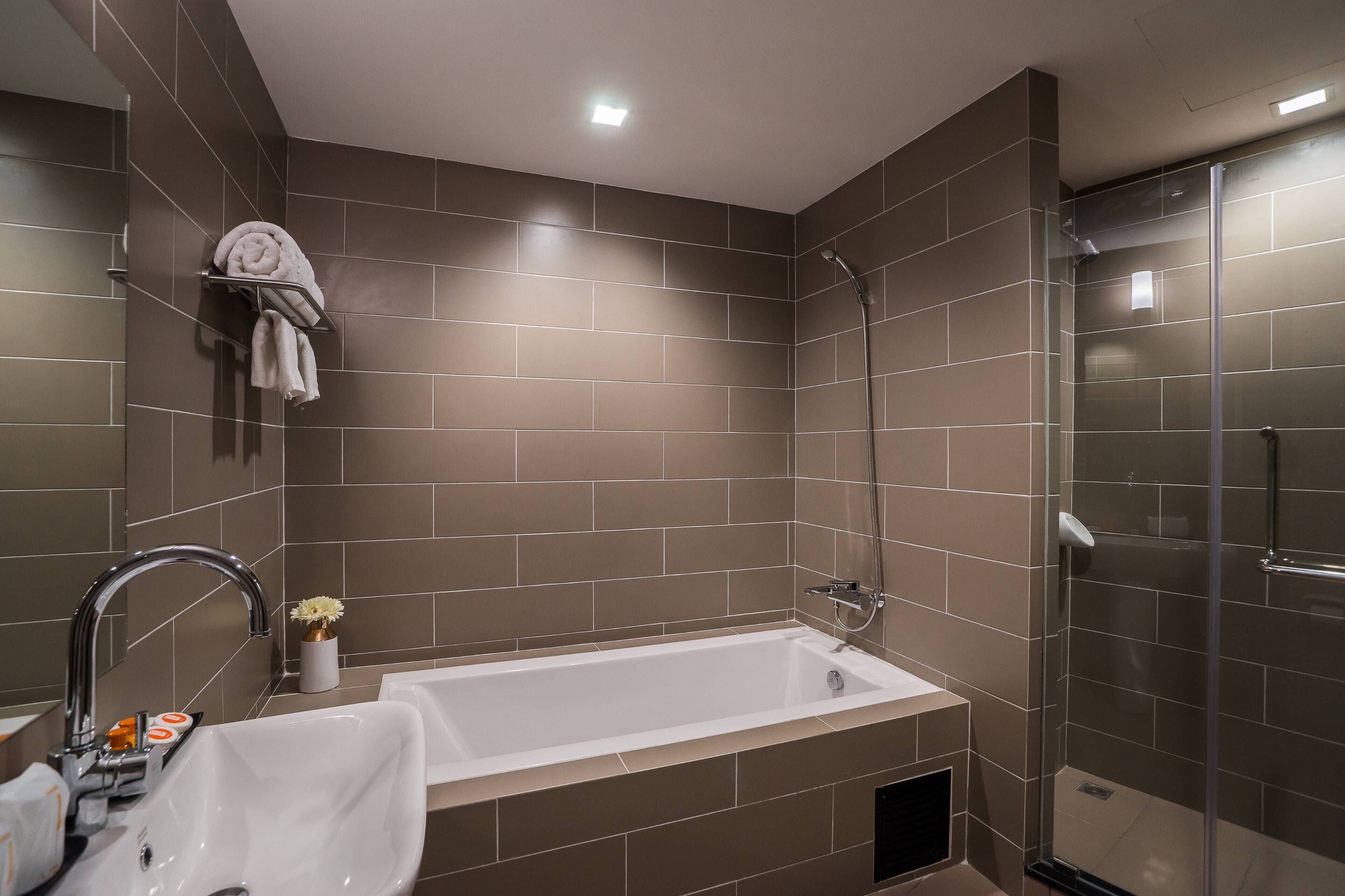 A modern bathroom with a bathtub, shower, and a towel rack with towels.