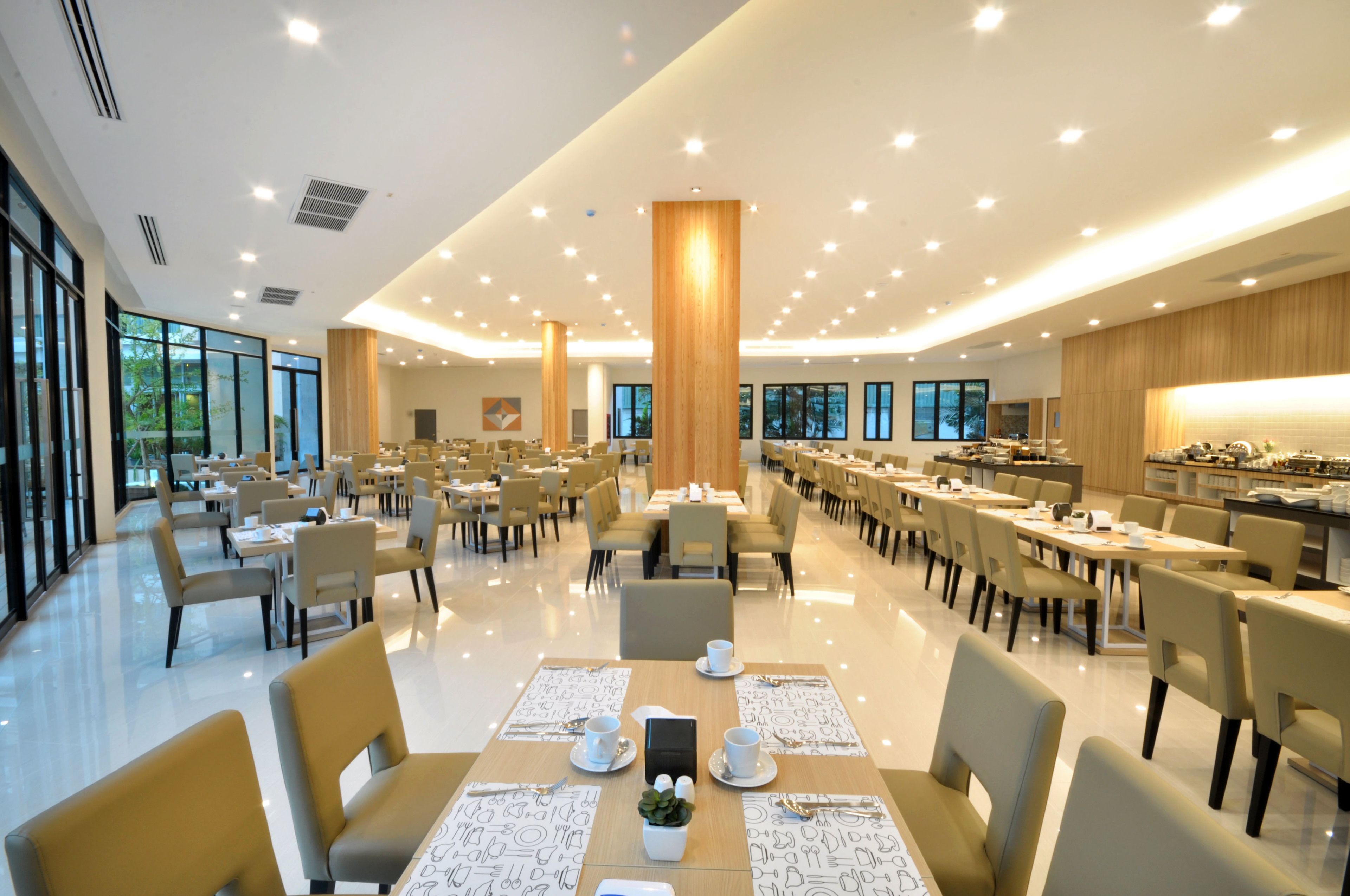 A spacious dining area with multiple tables and chairs, large windows, and a modern design.