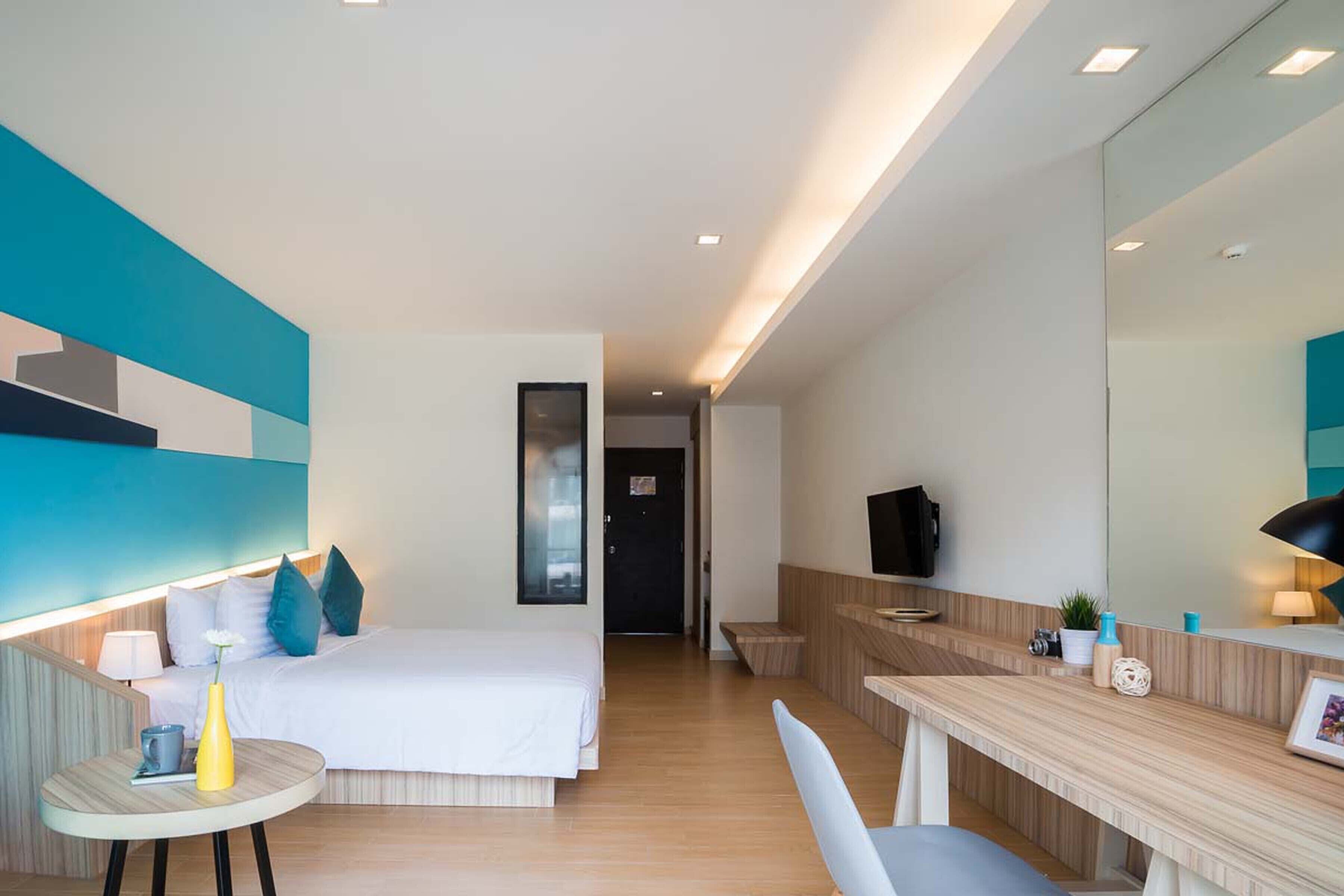 Ein modernes Hotelzimmer mit Bett, Nachttisch und Schreibtisch mit Stuhl.
