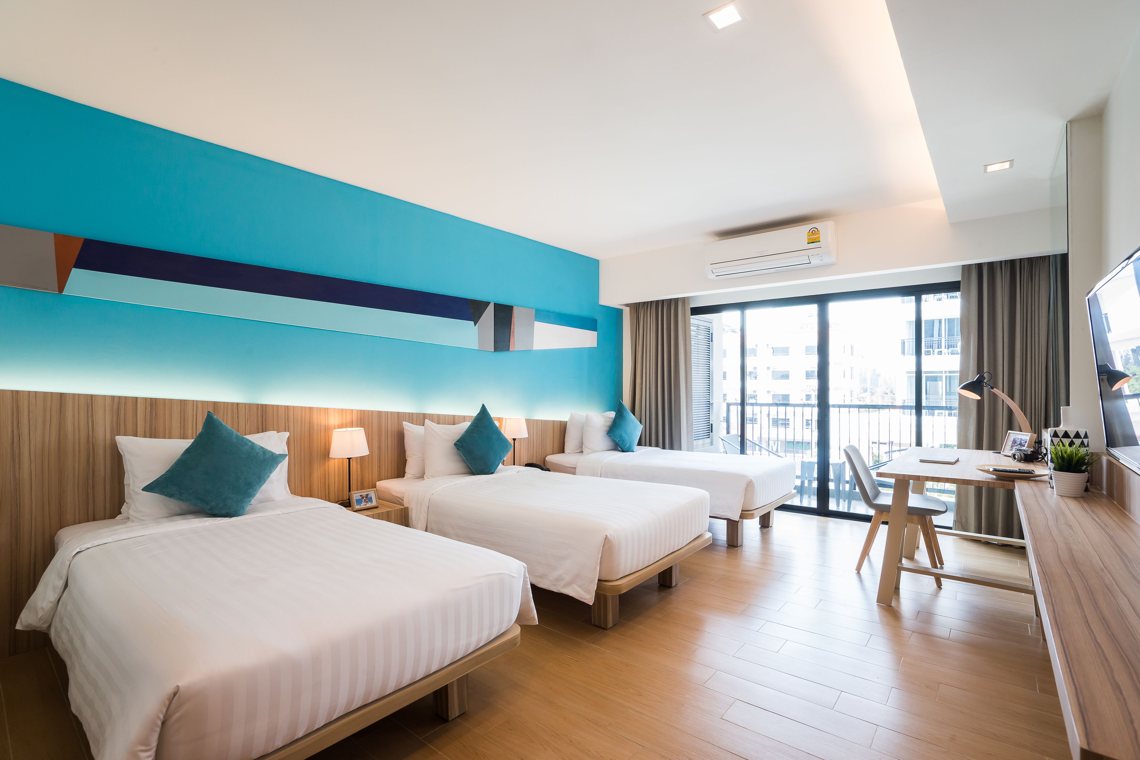 A hotel room with two beds, a desk, and a large window.