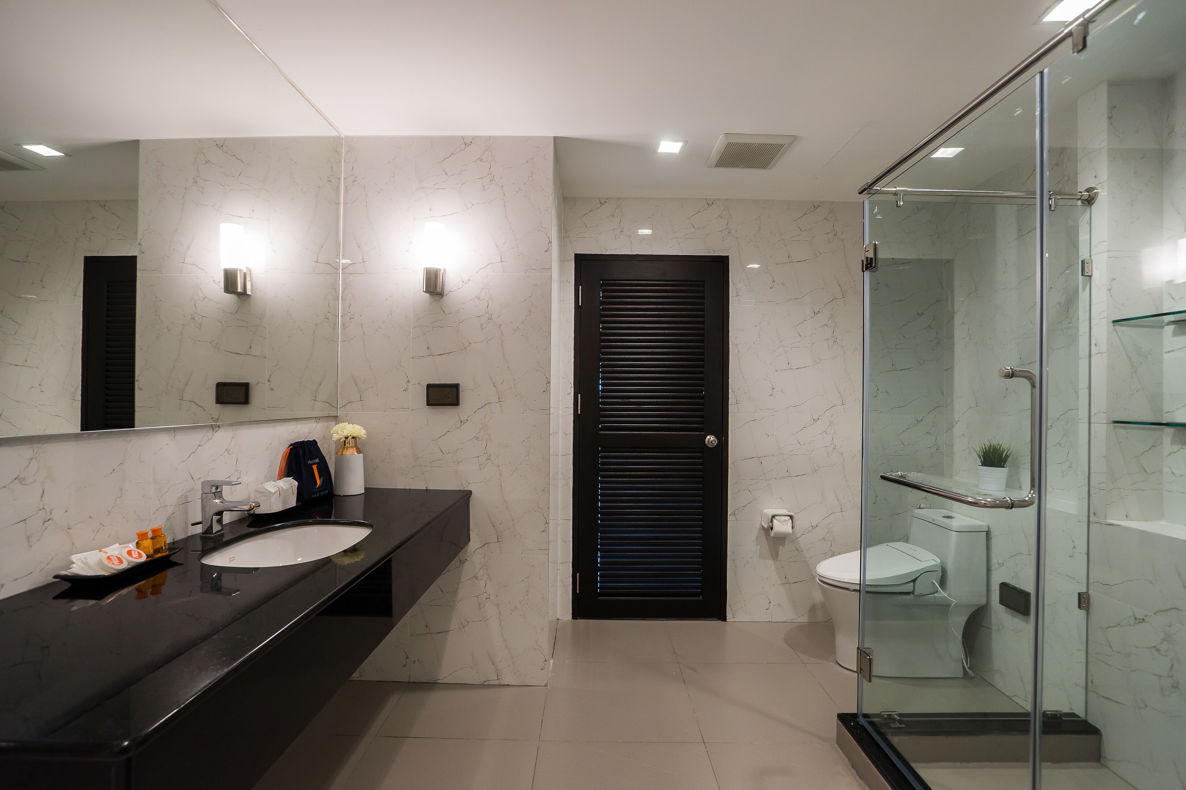 A modern bathroom with a black vanity, a glass shower enclosure, and a marble backsplash.