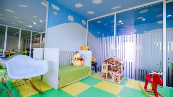 A child's playroom with a bed, rocking chair, and playhouse.