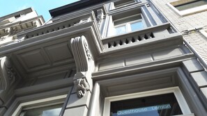 Facciata di un edificio con dettagli architettonici classici, tra cui decorazioni elaborate e una finestra con il cartello che riporta "Guesthouse Lemon".