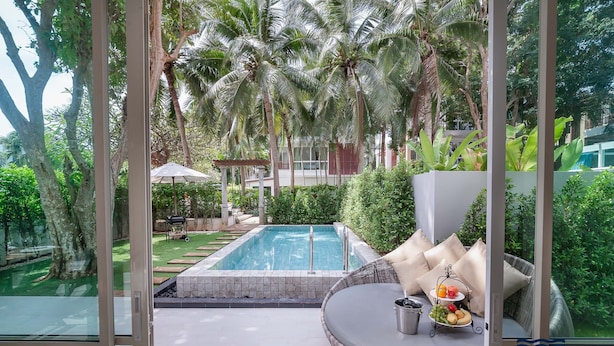 Eine private Villa mit Pool, Sitzgelegenheiten im Freien und üppiger Bepflanzung.