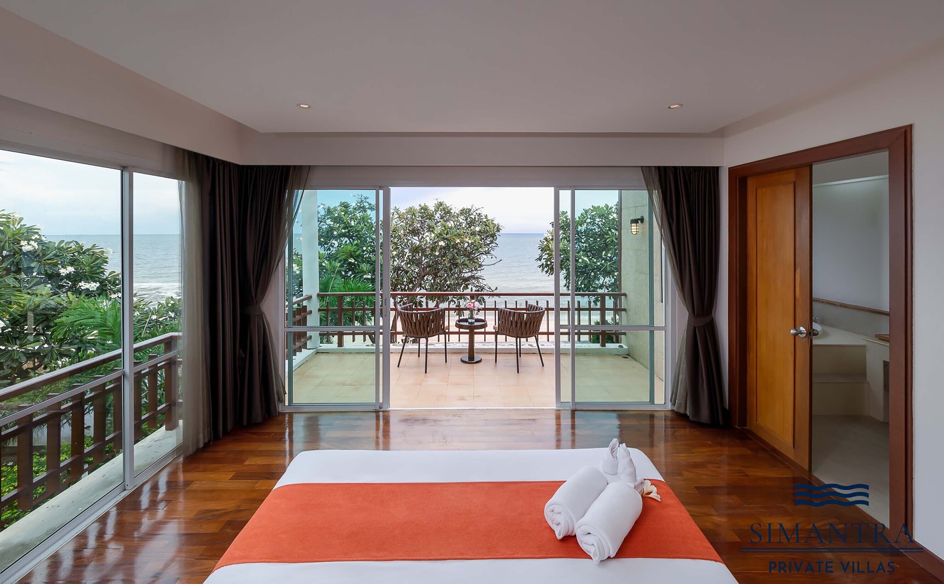 Una habitació d'hotel amb un balcó gran, un llit i vista al mar.