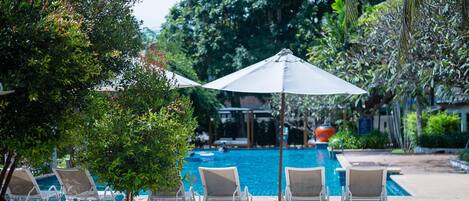Un espace aménagé au bord de la piscine, avec des chaises longues et un parasol.
