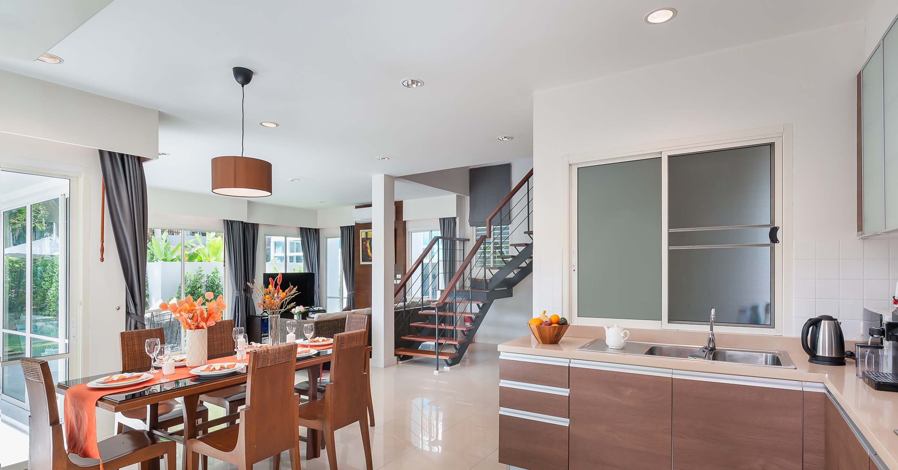 A modern kitchen with a large window, a built-in oven, and a stainless steel sink.