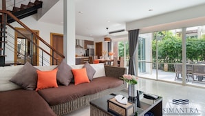 Ein modernes Wohnzimmer mit einem braunen Sofa, einem Essbereich und einer Küche.