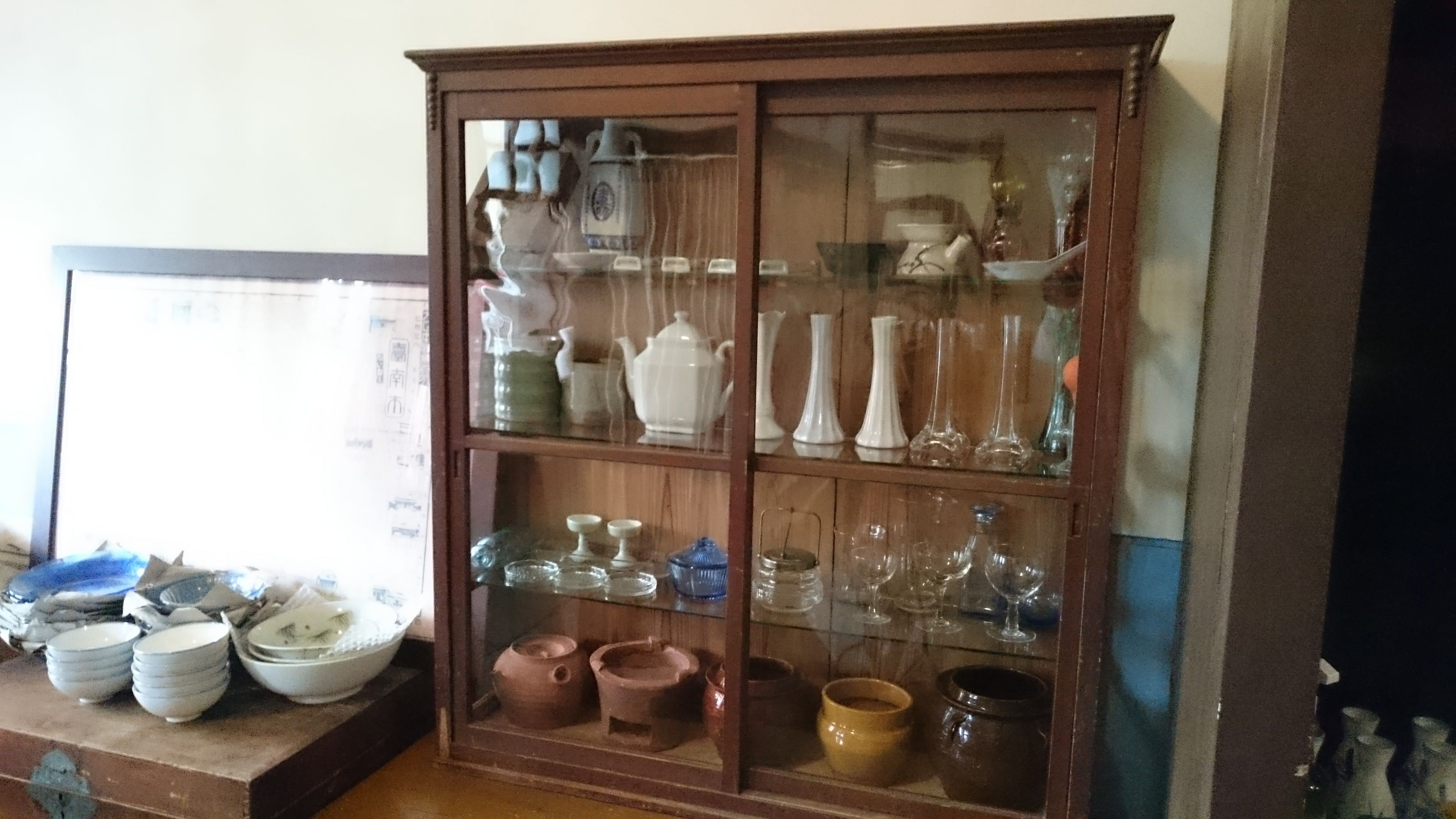 Ein Holzschrank mit mehreren Regalen, der verschiedene Gläser und Keramik zeigt.