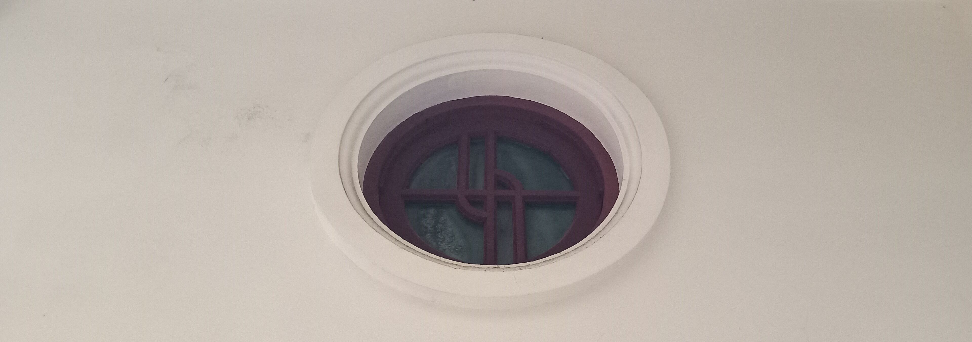 A circular window with a cross design on the glass.