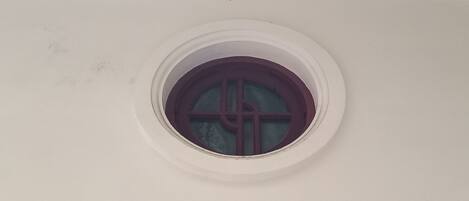A circular window with a cross design on the glass.