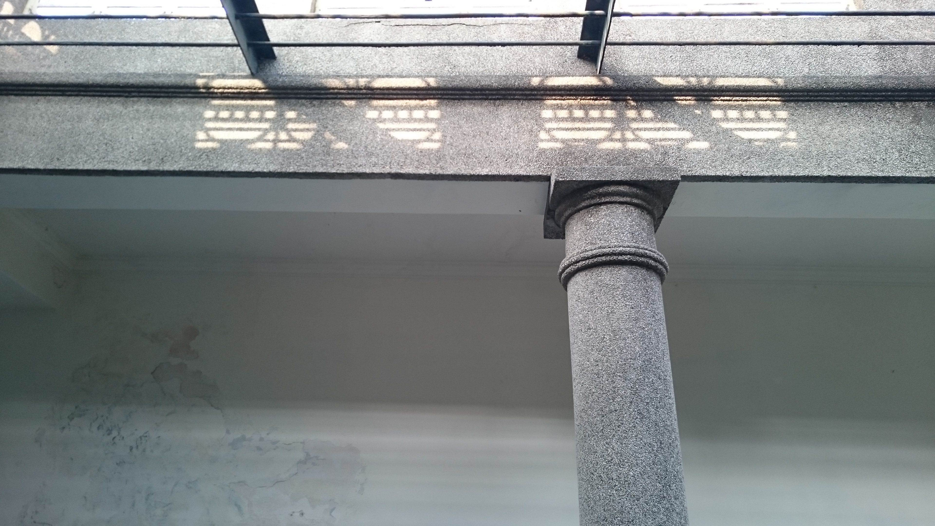 Un pilar de piedra que sostiene un techo con un diseño de cuadrícula.