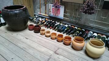 Variedad de botellas de vino y recipientes de cerámica sobre un suelo de madera.