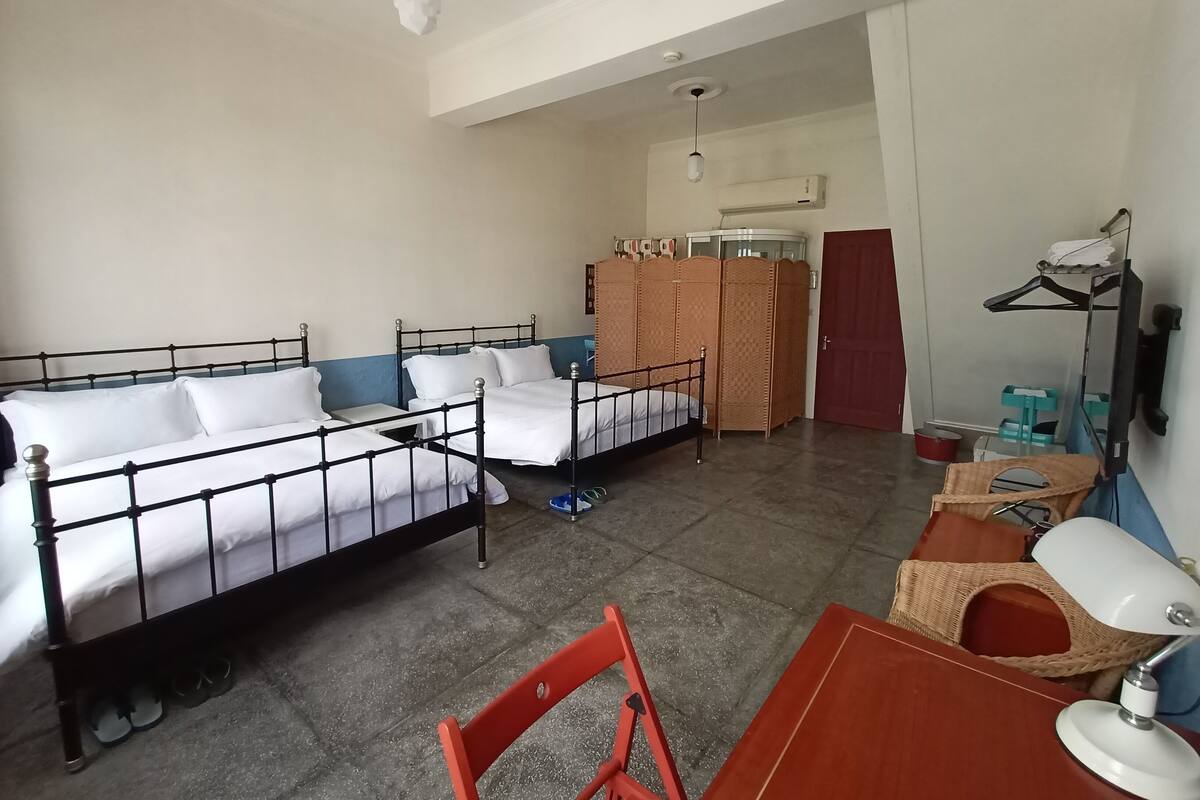 Een hotelkamer met twee bedden, een bureau, een stoel, een kledingkast en een kledingroede.