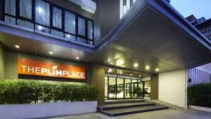 Een moderne hotelingang met een bord waarop “THE PLIMPLACE” staat.