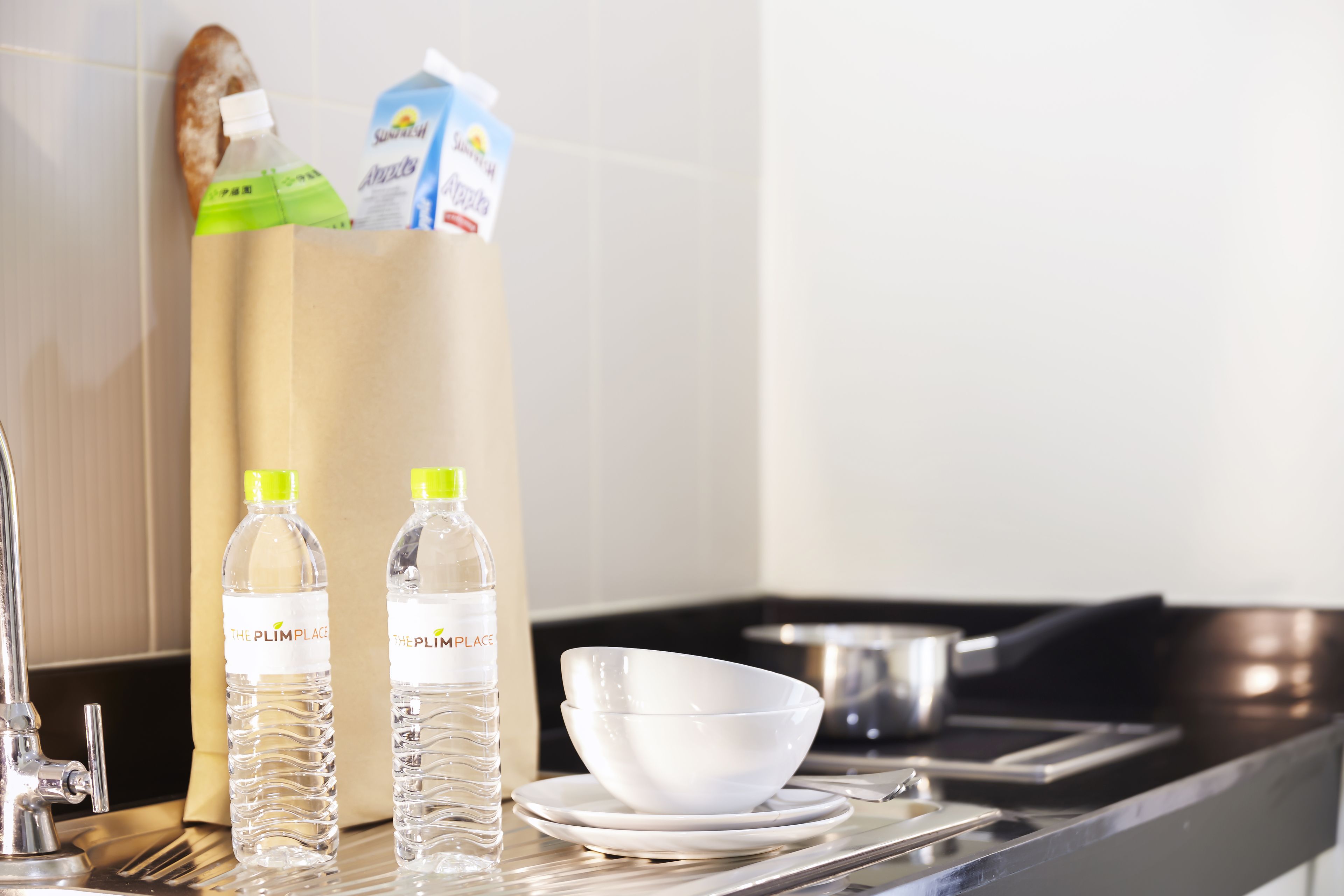 A kitchen counter with two water bottles, a white bowl, and a carton of milk.